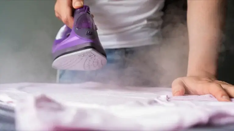 Close-up of a purple steam iron pressing clothes.