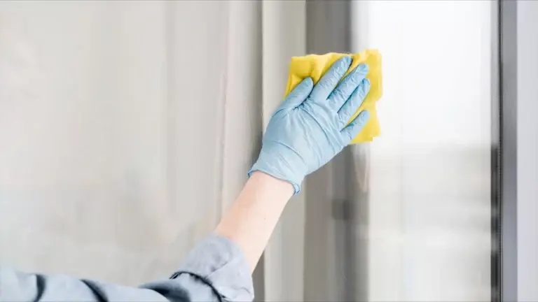 hand wiping glass window with yellow cloth