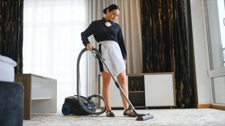 Hotel maid vacuuming carpet in room
