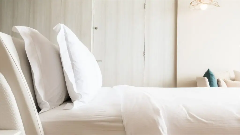 White hotel bed with pillows and wardrobe