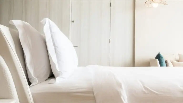 White hotel bed with pillows and wardrobe