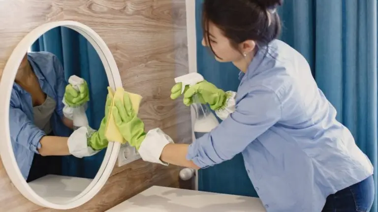 Woman cleaning bathroom mirror with spray