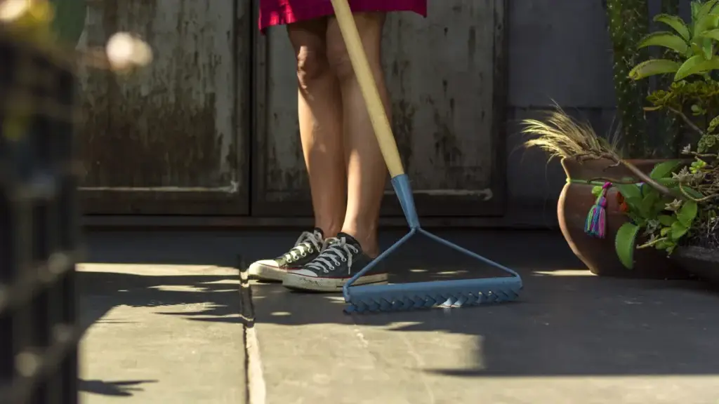 Woman sweeping outdoor patio with broom
