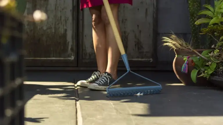 Woman sweeping outdoor patio with broom