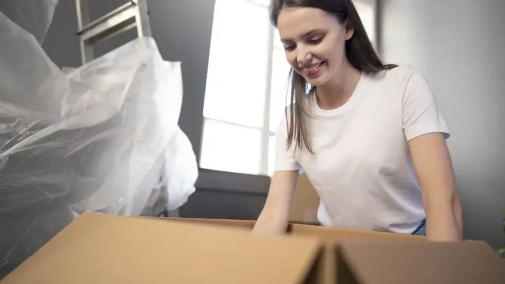Woman smiling while unpacking a box in her new home