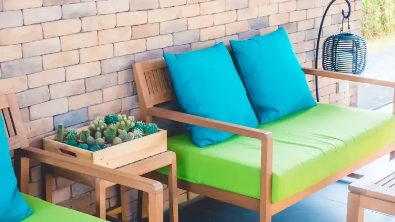 Green outdoor sofa with blue cushions and cacti